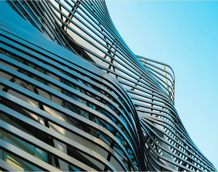 Curved modern architectural facade with wave-like metal panels against a blue sky - Neutrinos