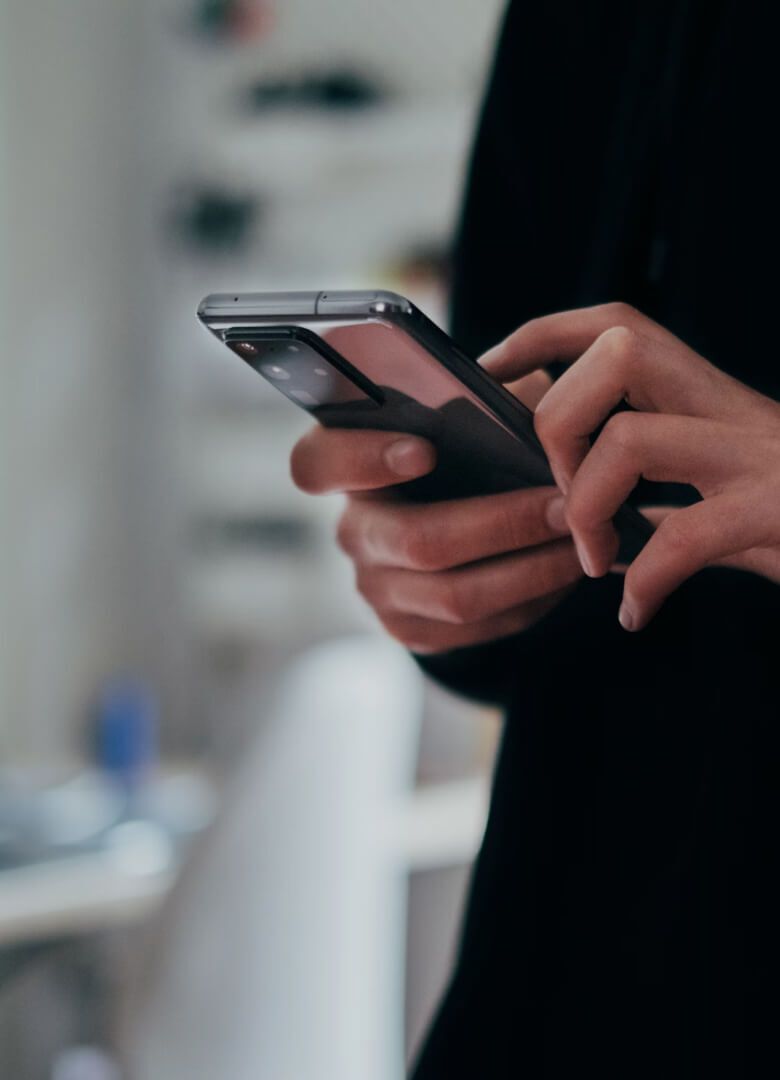 Close-up of hands using a smartphone in a blurred indoor setting - Neutrinos